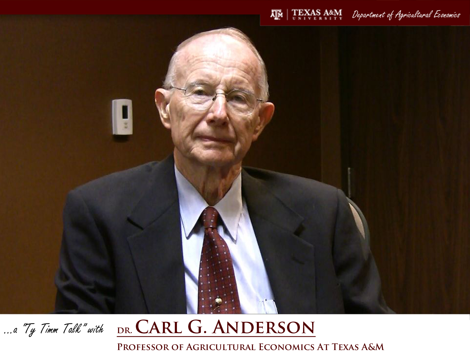 The words "A Ty Timm talk with Dr. Carl G. Anderson, professor of Agricultural Economics at Texas A&M" run across the bottom. Dr. Anderson is centered and seated in a brown room while wearing a black suit and maroon tie.