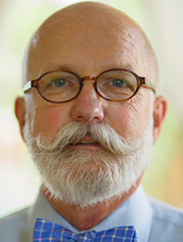 Art Smith in white button up and blue bow tie in front of white and green background.