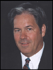 Creed Ford in a black suit and tie against a black backdrop.