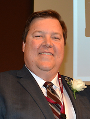 Daniel Haile smiling in a black suit at his induction event