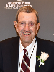 David Winters smiling in a black suit and red striped tie with a white flower pinned to the lapel. The background is grey with "Agriculture and life sciences, Texas A&M" in white print