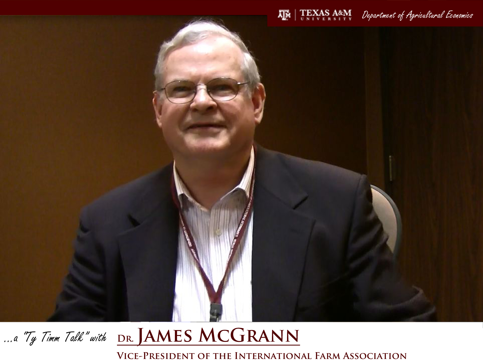 The words "a ty timm talk with Dr. James McGrann - Vice-President of the International Farm Association" run along the bottom. Mr. McGrann is seated and wearing a black suit, smiling in front of a brown background.