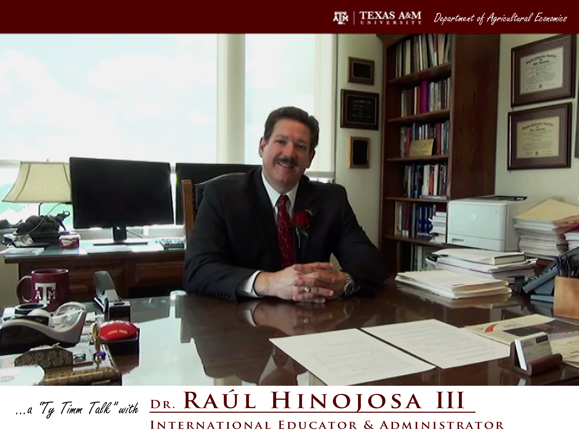 The words "a ty timm talk with Dr. Raul Hinojosa III - International Educator and Administrator" run along the bottom. Dr. Hinojosa is seated and wearing a black suit, smiling at a large brown desk.