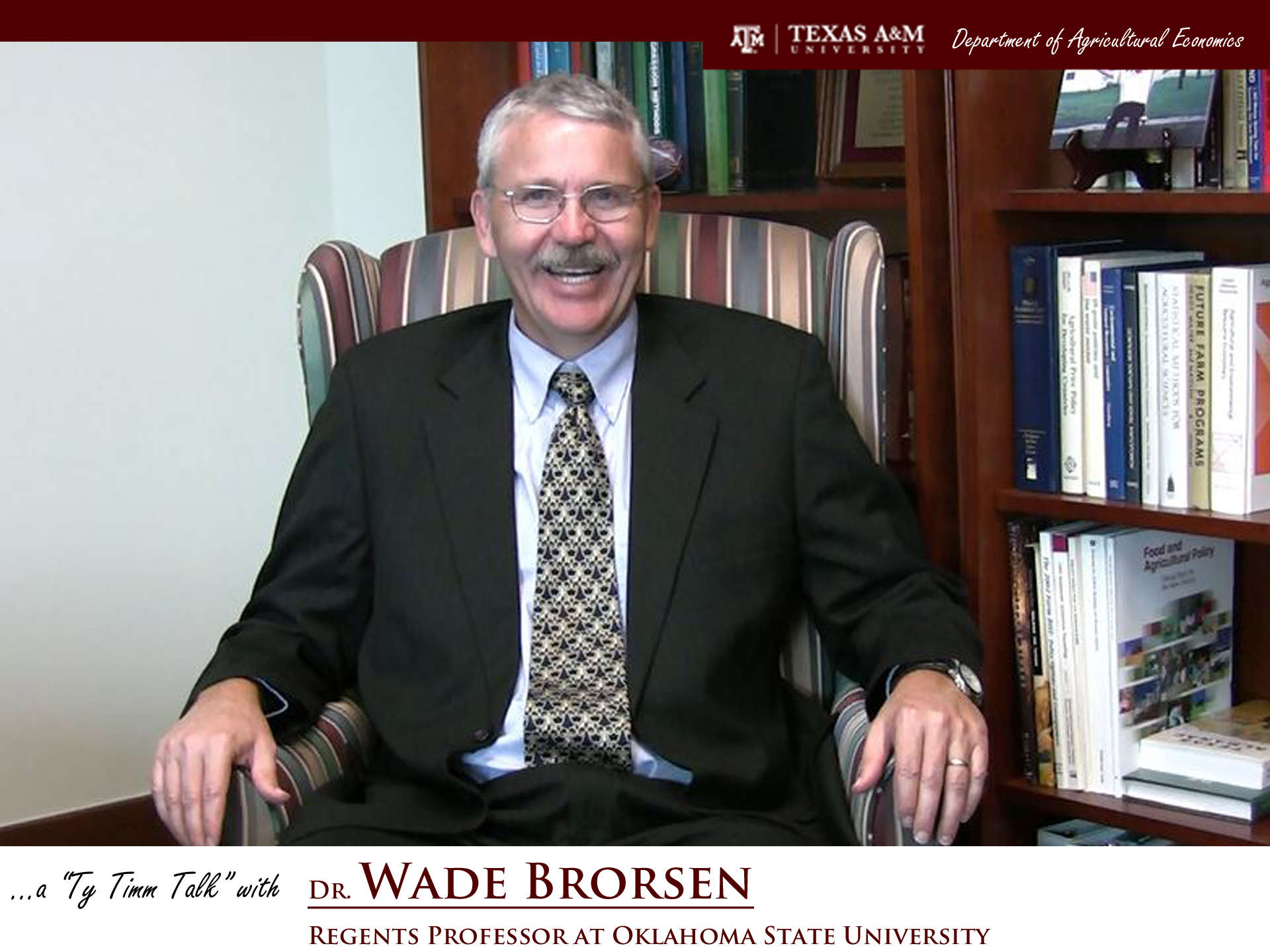 The words "a ty timm talk with Dr. Wade Brorsen - regents professor at Oklahoma State University" run along the bottom. Dr. Brorsen is seated in a striped chair in front of a full bookcase, wearing a black suit and scalloped green and gold tie.