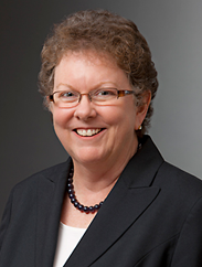 Cathy Lemieux smiling in a black suit against a grey backdrop