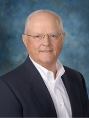 Lynn Elliott smiling in  a dark blue suit against a blue backdrop.