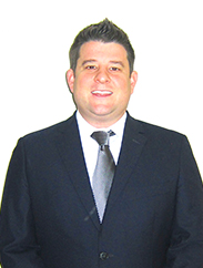 Matt Bobbitt smiling in front of a white backdrop wearing a dark blue suit and tie.