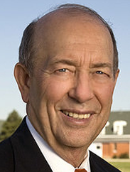 Robert Whitson smiling in a black suit against an outdoors background